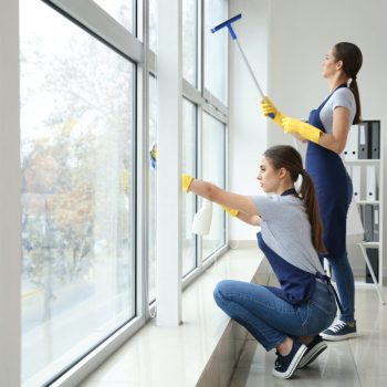 Janitors washing window in office